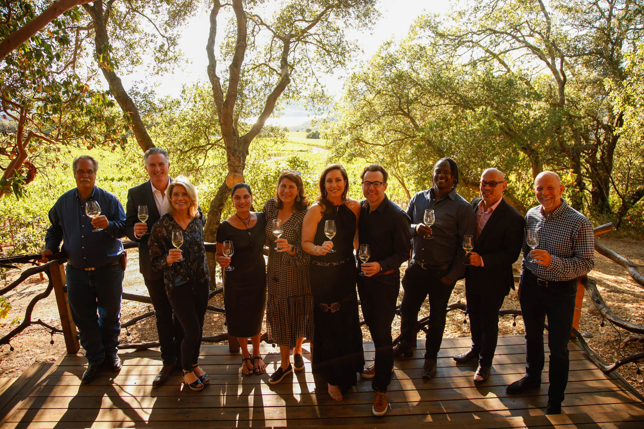 Ten people standing with wine glasses looking at the camera